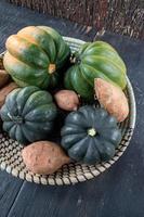 fall harvest of sweet potatoes and acorn squash in basket flat lay photo
