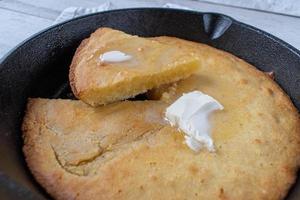 sliced yellow corn bread with butter in cast iron pan photo