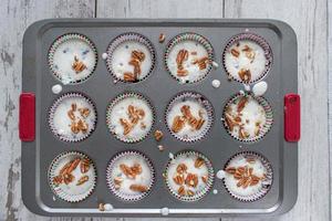 raw blueberry muffin batter filled muffin cups topped with pecans flat lay photo