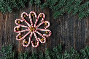 candy canes in a flower design with glitter gold balls with green tree border with copy space flat lay photo