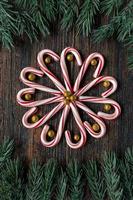 candy canes in a flower design with glitter gold balls with green tree border with copy space flat lay photo