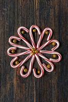 candy canes in a flower design with glitter gold balls on rustic wood table flat lay photo