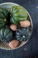 fall harvest of sweet potatoes and acorn squash in basket flat lay photo