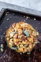 roasted acorn squash bowls filled with bread stuffing, nuts, and herbs on baking sheet photo
