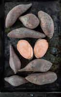 raw and whole sweet potato yams on baking tray flat lay photo