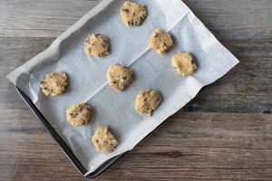 raw unbaked homemade oatmeal cookies on baking sheet flat lay photo
