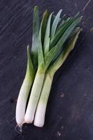 tallos de puerro de verduras frescas sobre una mesa de madera plana foto