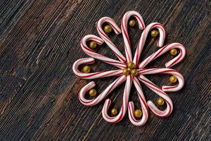 candy canes in a flower design with glitter gold balls on rustic wood table flat lay photo