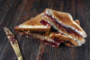 Sándwiches desordenados de mantequilla de maní y mermelada cortados por la mitad en una pila foto