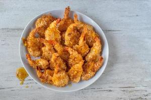 Fried Coconut Shrimp with tails drizzled with sauce flat lay photo