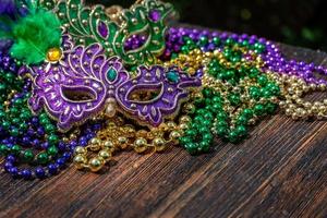 Mardi Gras color beads with masks on wooden table in sunlight photo