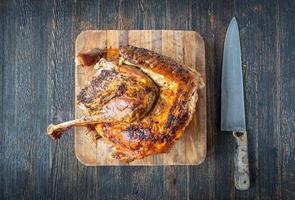 preparing to slice baked golden brown half turkey on cutting board flat lay