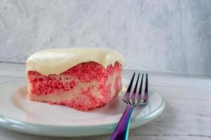 Slice of yellow jello cake with pudding frosting on plate with fork photo