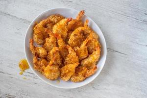 Fried Coconut Shrimp with tails drizzled with sauce flat lay photo