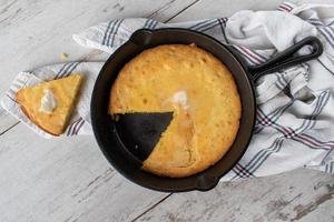 baked yellow corn bread with butter in cast iron pan top view