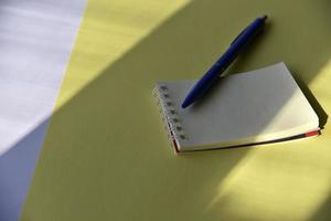 Blue fountain pen and notepad on a yellow background photo