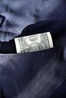 A wad of dollars in the pocket of blue pants photo