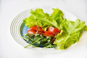 Salad on a white plate tomatoes greens and peas. White background. photo