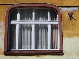 ventanas de colores blanco rojo de estilo antiguo con cortina de encaje en la pared amarilla foto