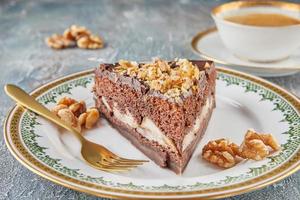Chocolate cake with pears and walnuts on plate with cup of coffee