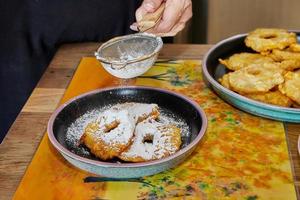 Cooking apple pancake. The chef sprinkles powdered sugar on stacked apple donuts on plate photo