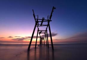 Scene of beautiful sunset and old wooden bridge at Pilai beach photo