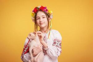 jovencita con una corona en la cabeza y vestida con una camisa bordada con un gato en los brazos. mascota. foto