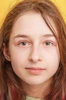 Portrait of a teenage girl on a yellow background. The girl is in a positive mood. photo