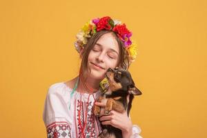 Teen girl in an embroidered shirt with a black dog in her arms. Girl and pet. photo