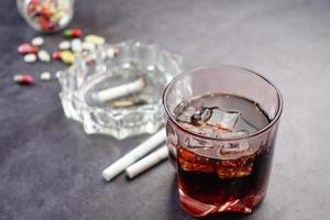 alcohol, pastillas y cigarrillos en la mesa foto