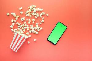 top view of smart phone and popcorn on table photo