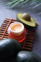 Close up of beauty cream and avocado on table