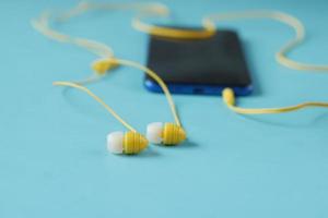 teléfono inteligente y auriculares sobre fondo de madera. foto