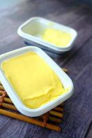 Mantequilla fresca en un recipiente con pan sobre fondo blanco. foto