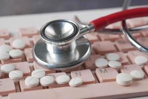 Close up of pills and stethoscope on keyboard photo