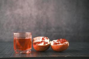 glass on pomegranate juice on black background . photo