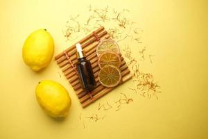 botella de aceite esencial y limón sobre fondo amarillo