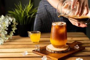 vaso de espresso con jugo de naranja sobre una mesa de madera y espacio para copiar, cóctel de verano, café frío o té negro, bebida fría.