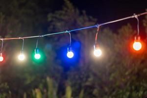 color lamps. Modern Abstract background of lamps. Colorful lightbulbs blurred nature background. Romantic mood string light. Red, moody, hanging soft lights under the decorated tree. photo