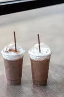 two iced chocolate or mocha coffee in take away glass topped with milk foam cream at cafe photo