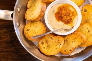 Selective focus, Cheese dip with butter and garlic bread slices. Fresh golden toasts served with cheesy sauce. top view photo