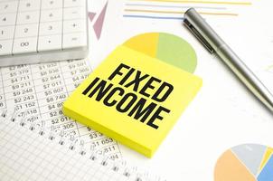 FIXED INCOME text on sticker on calculator with pen, pencil on white background photo