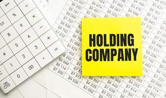 HOLDING COMPANY text on yellow sticker on notepad photo