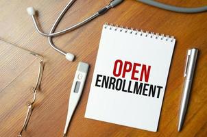 The text open enrollment is written on notepad near a stethoscope photo