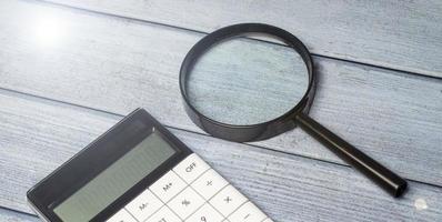 calculator and magnifying glass on wooden table photo