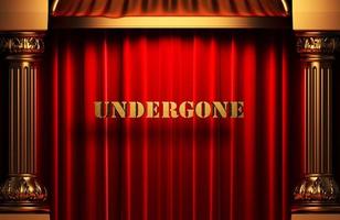undergone golden word on red curtain