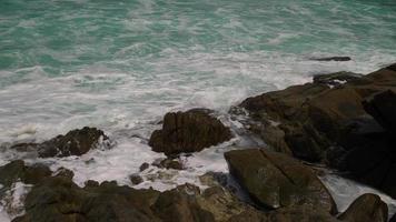 close-up das ondas do mar batem nas rochas da costa criando uma explosão de água. bela praia tropical. incrível litoral arenoso com ondas do mar branco. conceito de natureza, marinha e verão. video