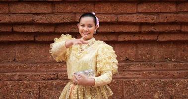 prise de vue à la main, belle jeune femme en costume traditionnel thaïlandais profiter des éclaboussures d'eau dans le temple lors du festival de songkran. nouvel an thaïlandais, culture thaïlandaise avec festival de l'eau