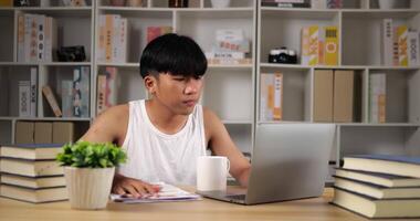 Portrait of Tired asian man in singlet using laptop and looking document at home. Sleepy man working at home,thinking and feeling thoughtful. Working from home overload at night in new normal. video