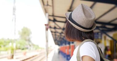 portret zijaanzicht van jonge Aziatische reizigersvrouw die een foto op camera neemt bij het treinstation. vrouw die naar de camera kijkt. vervoer, vakantie en reizen concept. video